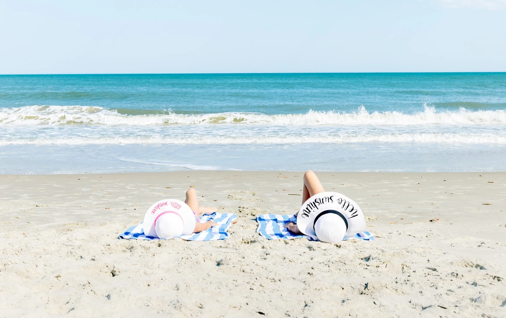 two people lying on towels on a beach