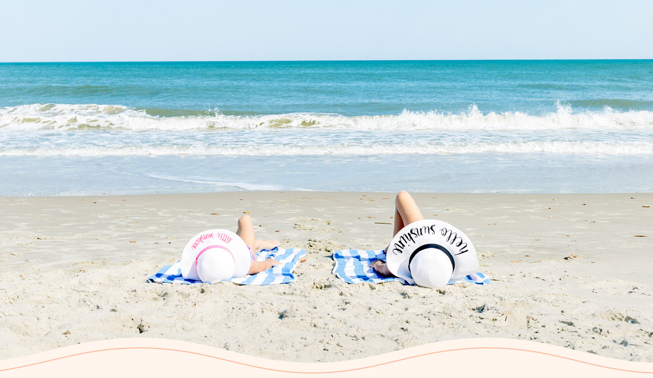 two people lying on towels on a beach