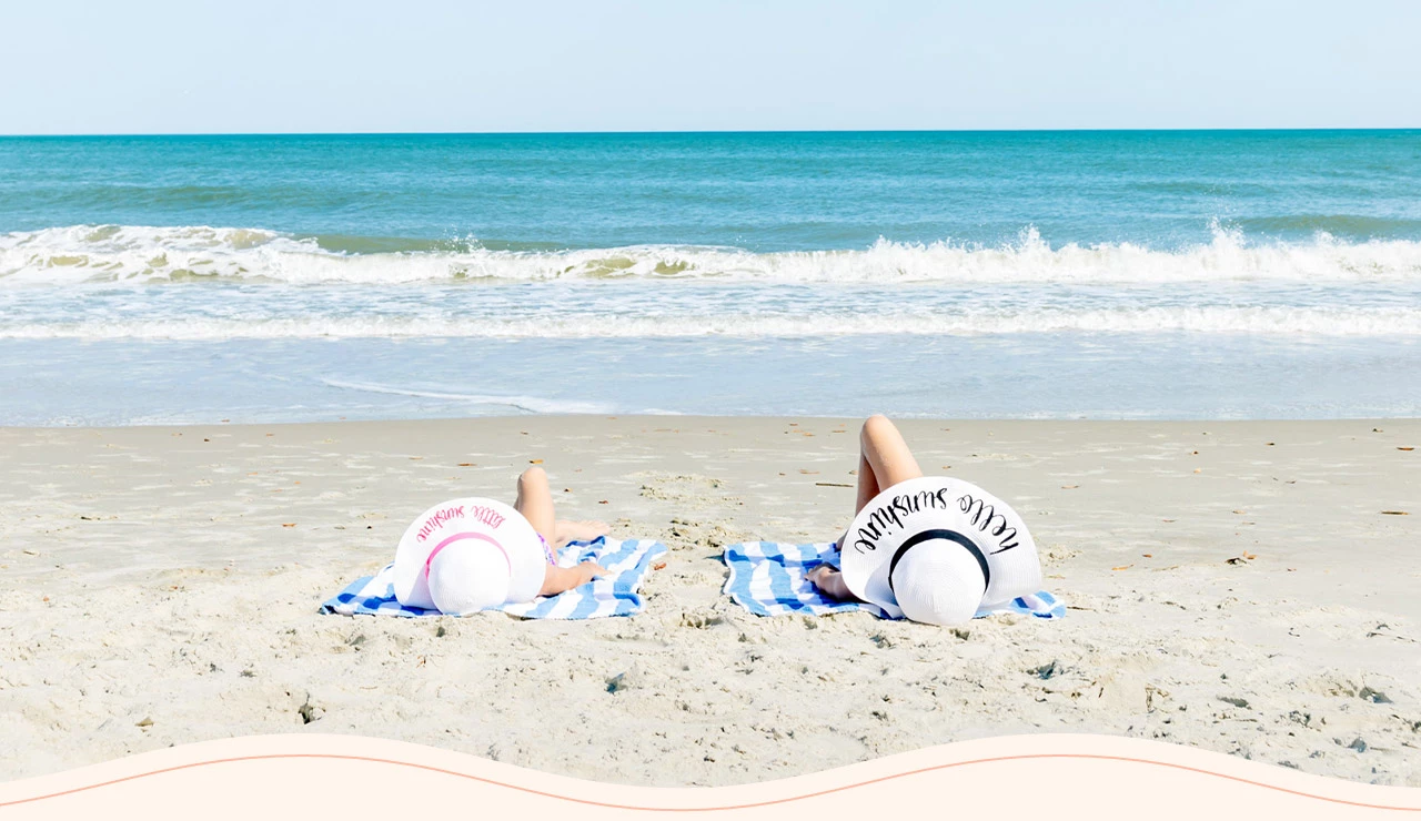 two people lying on towels on a beach