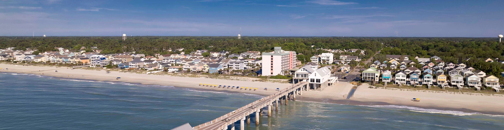 a bridge over a beach with buildings and trees