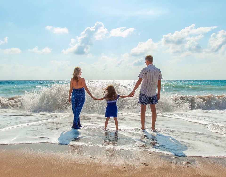 a family standing on a beach holding hands