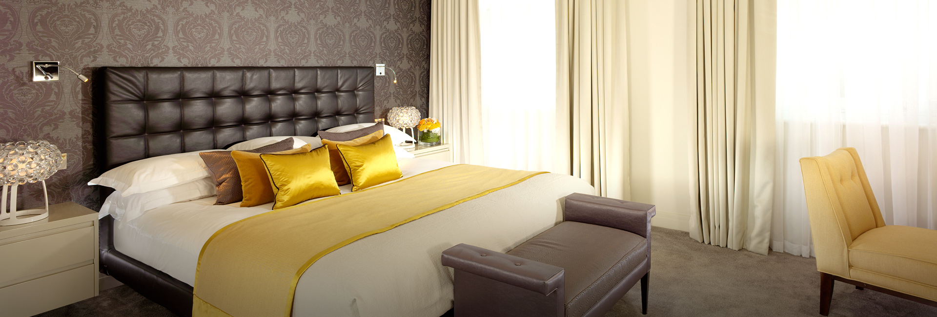 a bed with yellow pillows and a brown leather couch