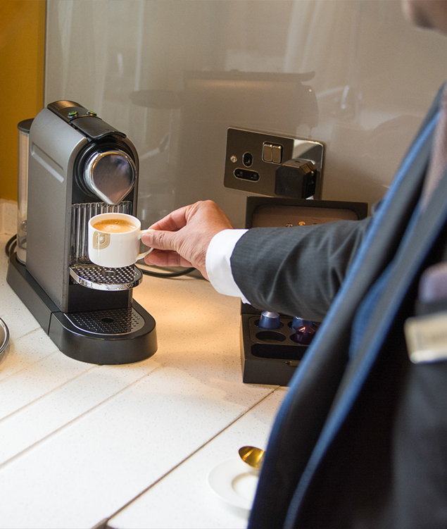 a person pouring a cup of coffee into a coffee machine