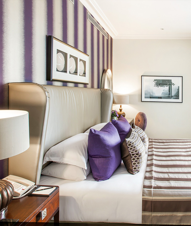 a bed with purple pillows and a lamp