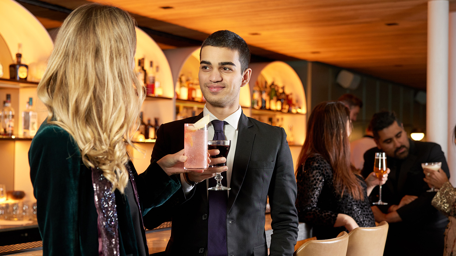 a man holding a drink and a woman in a bar