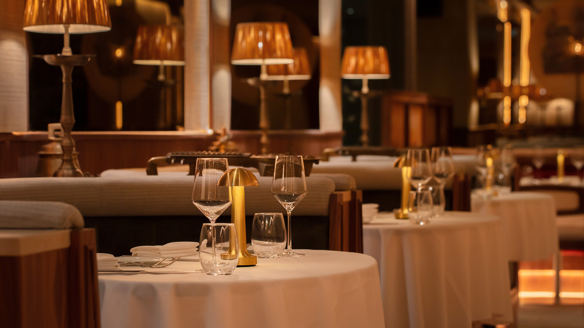 a table with wine glasses and a gold lamp