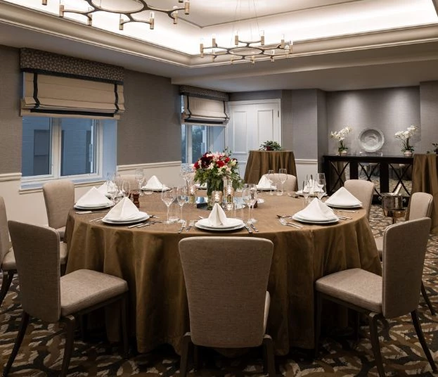 a round table with a brown cloth covered cloth and a flower arrangement
