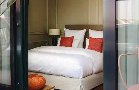a bed with white sheets and red pillows