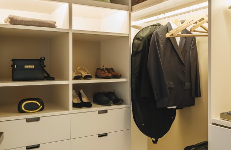 a closet with shoes and a coat on a swinger
