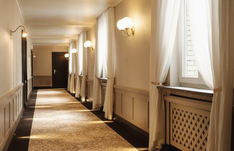 a long hallway with white curtains and a door
