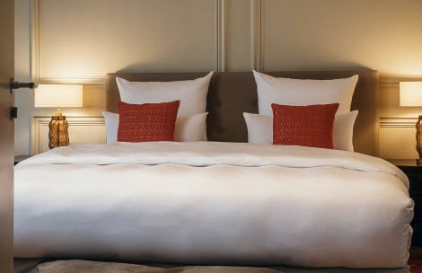 a bed with white sheets and red pillows
