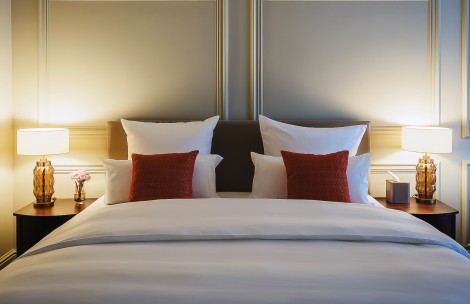 a bed with white sheets and red pillows