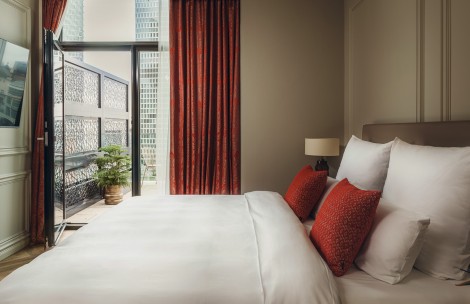 a bed with red pillows and a lamp in a room with a balcony