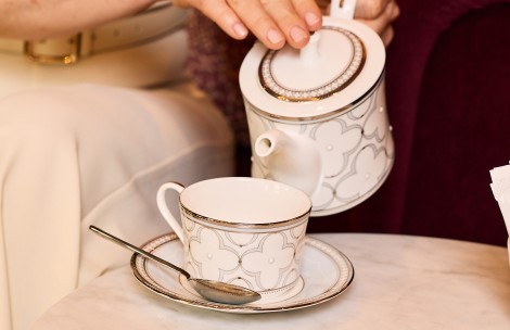 a teacup and saucer with a teapot and a spoon