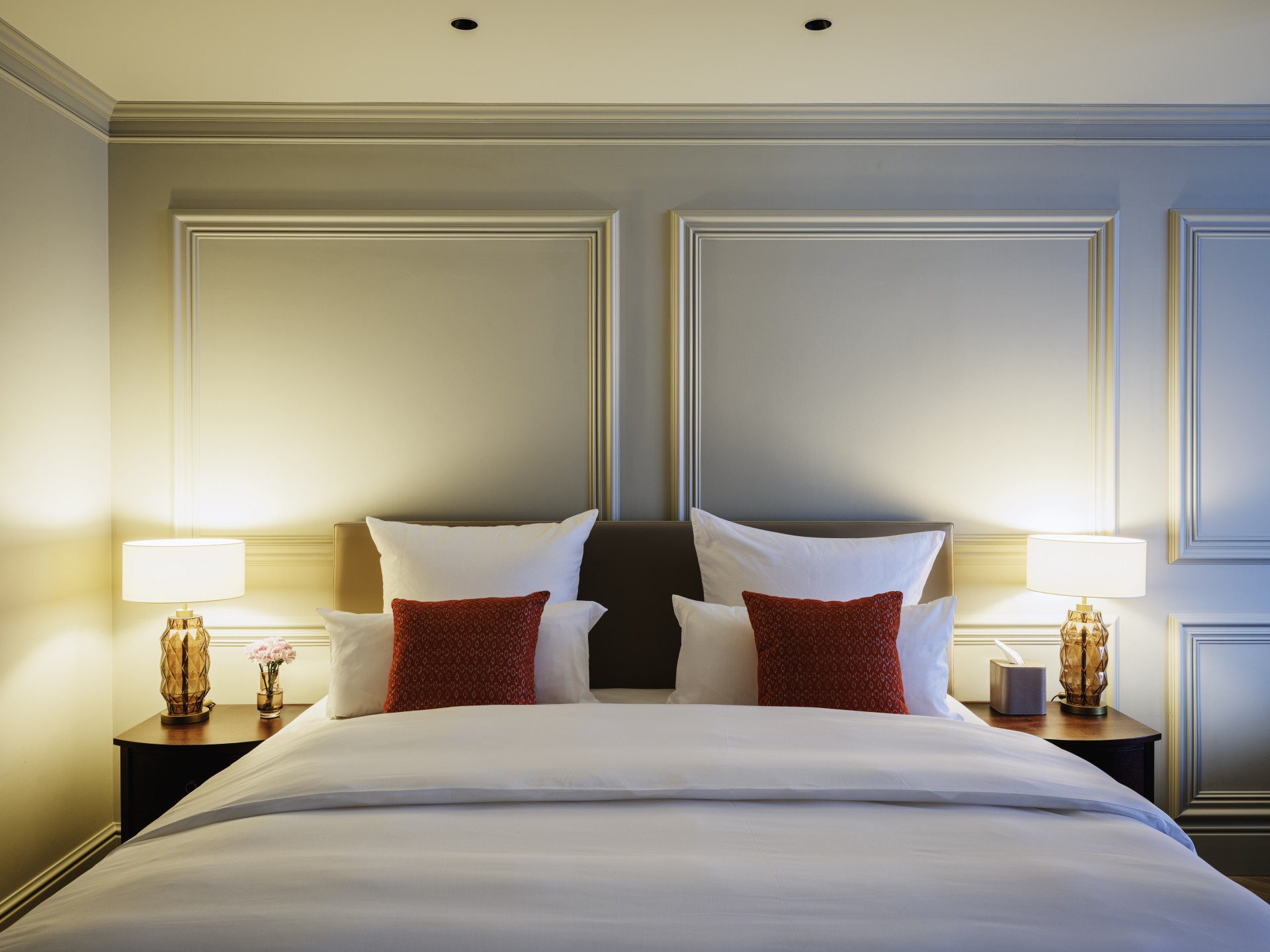 a bed with white sheets and red pillows