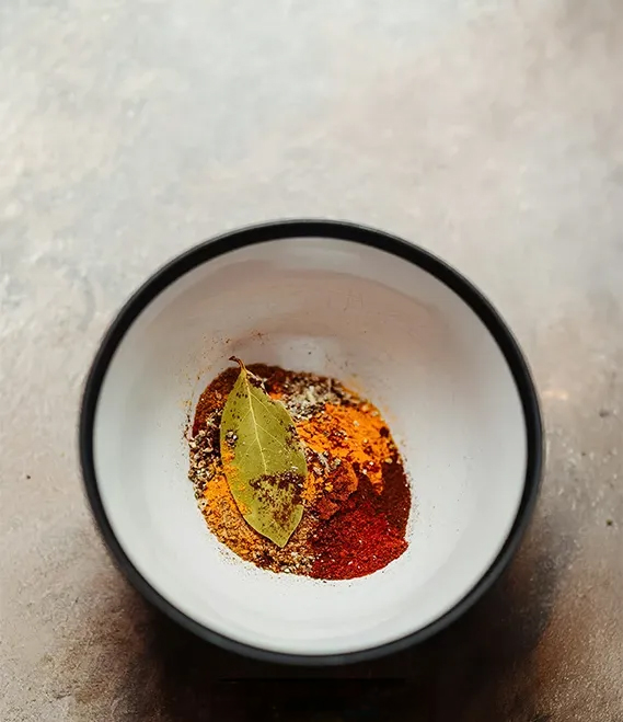 a bowl with spices and a leaf in it