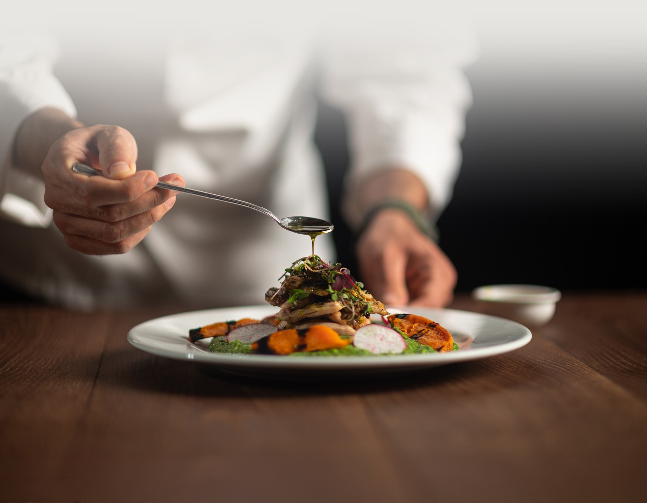 a person pouring a spoon over a plate of food