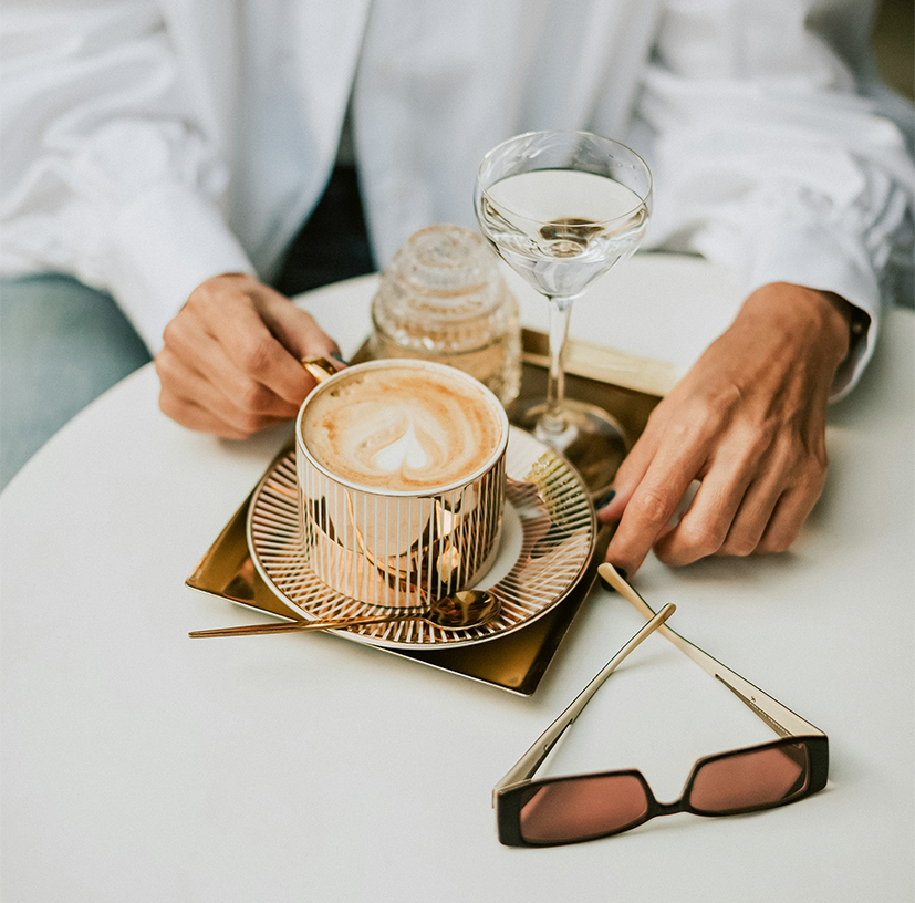 a person sitting at a table with a cup of coffee and glasses