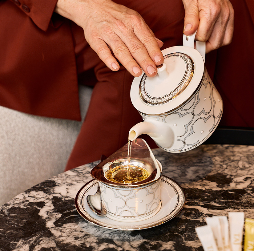 a person pouring liquid into a tea cup