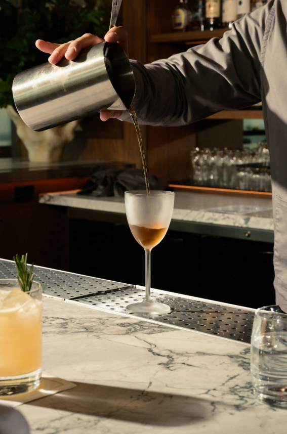 a person pouring a drink into a glass
