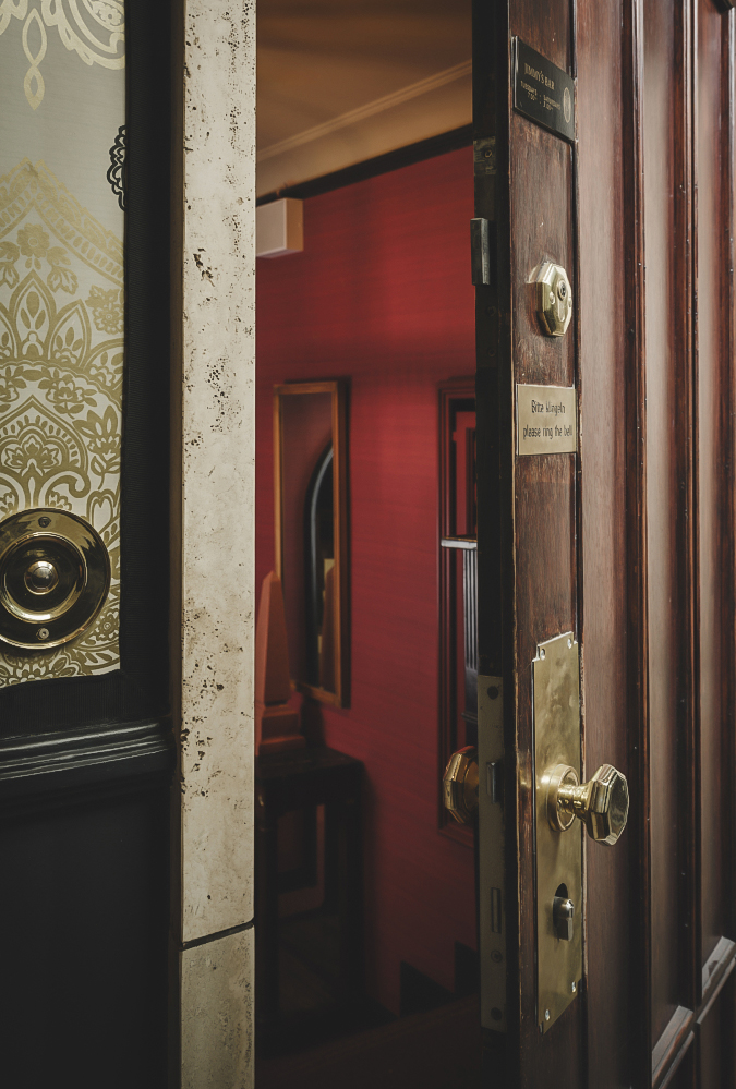 a door with gold knobs and a red wall