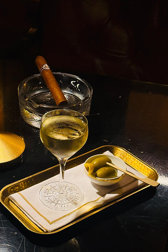 a glass of wine and olives on a tray with a cigar