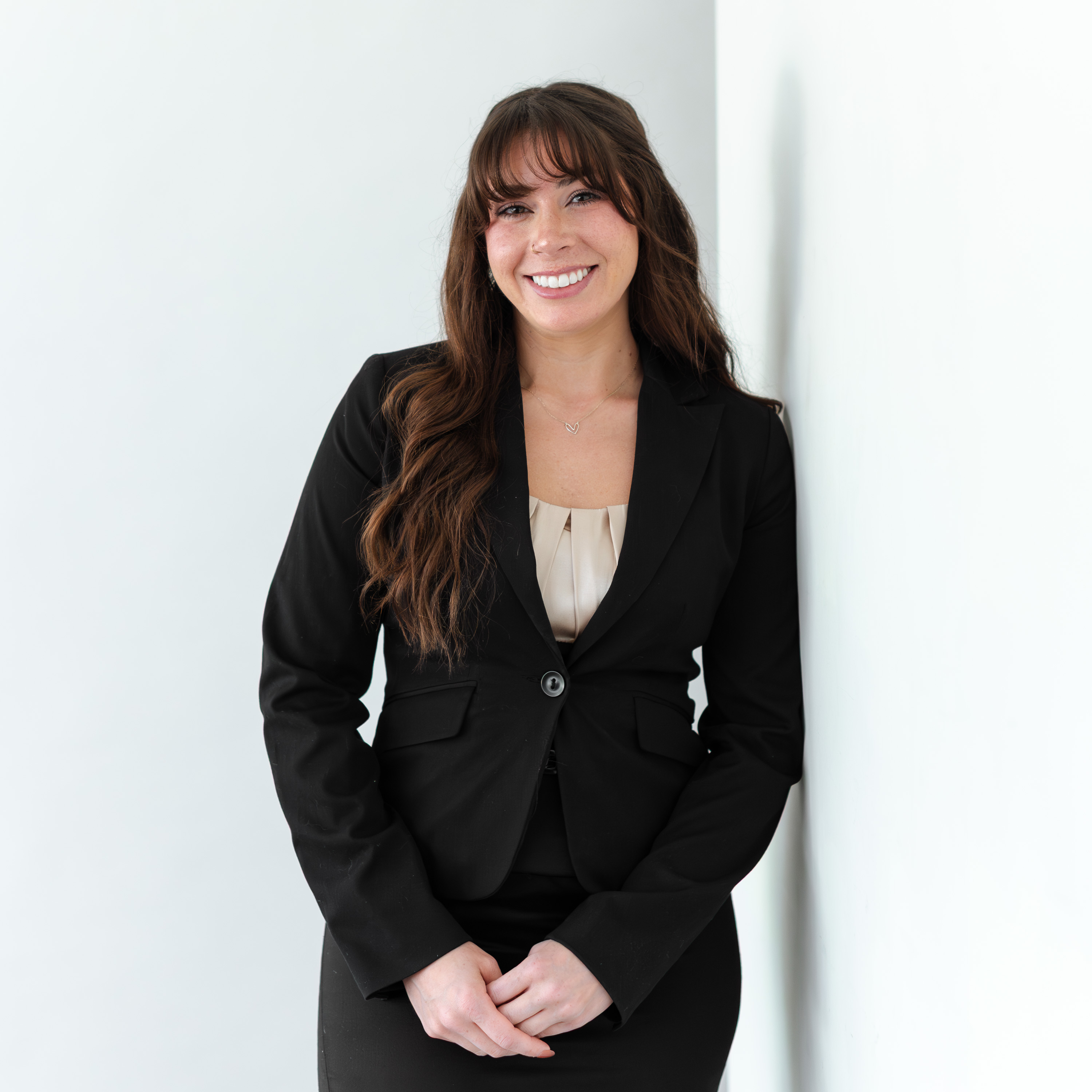 a woman in a black suit leaning against a wall