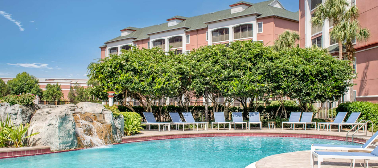 a pool with chairs and trees in the background
