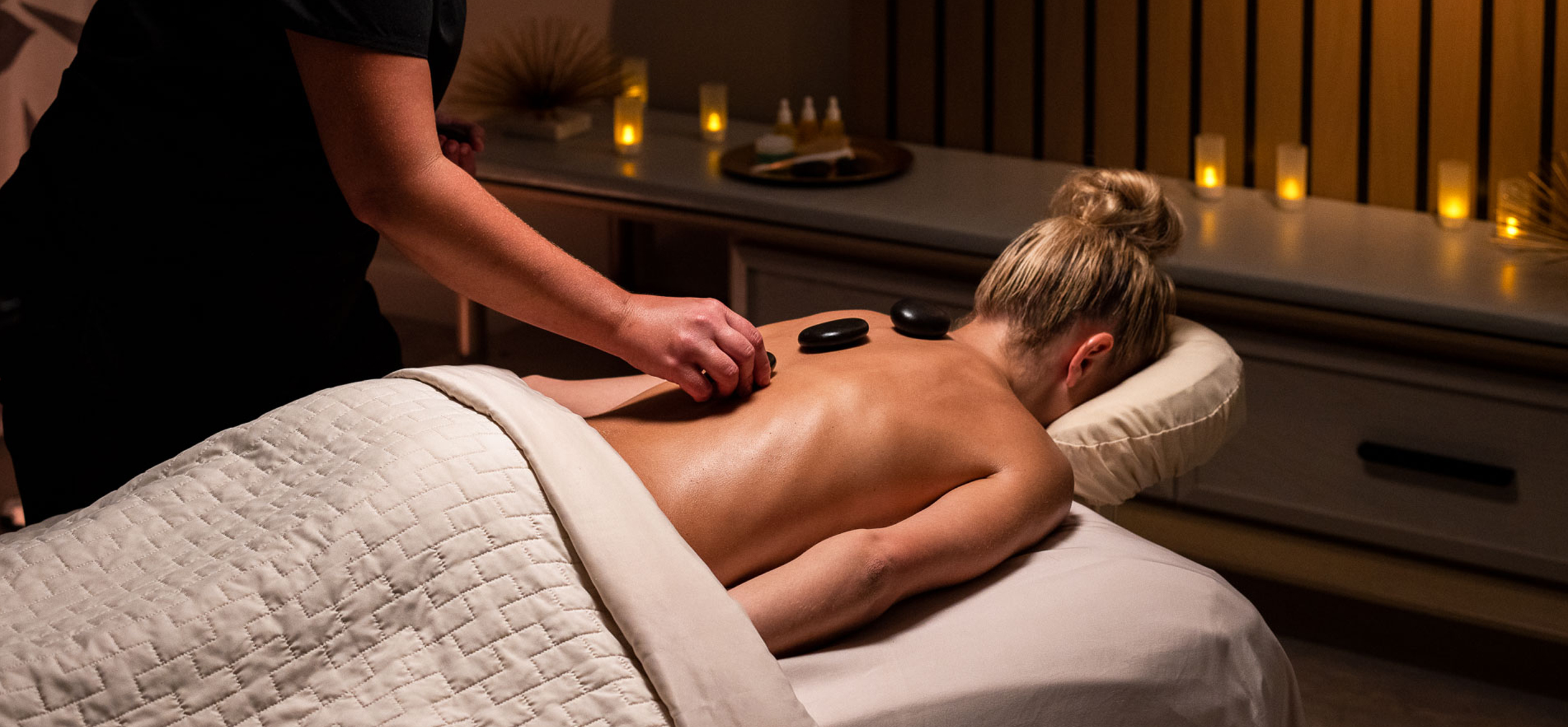 a woman lying down on a bed with a massage stone on her back