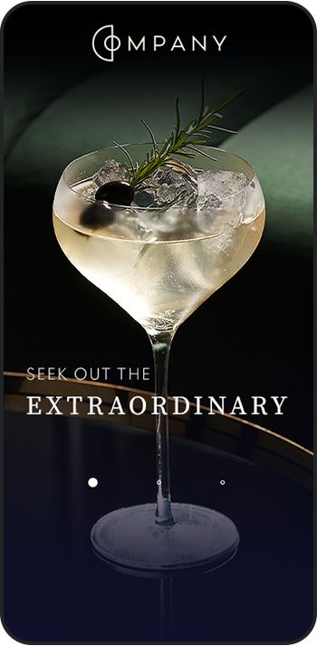 a glass of liquid with ice and olive