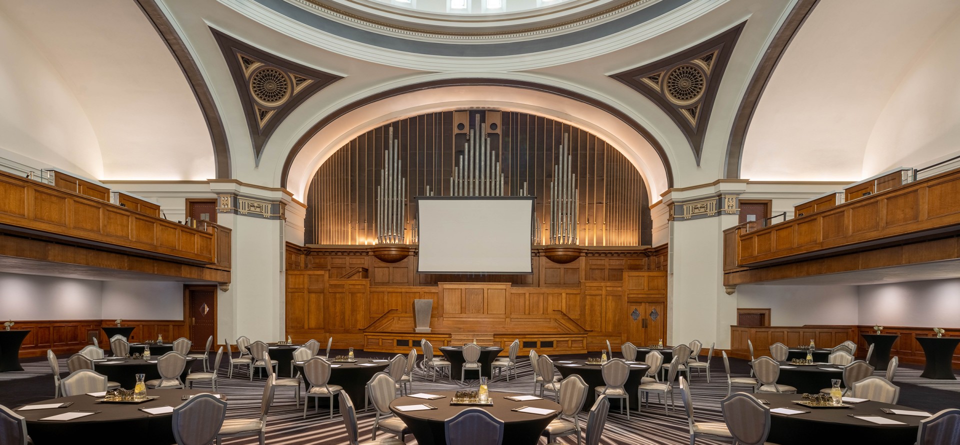 a room with a projector screen and a large organ pipe