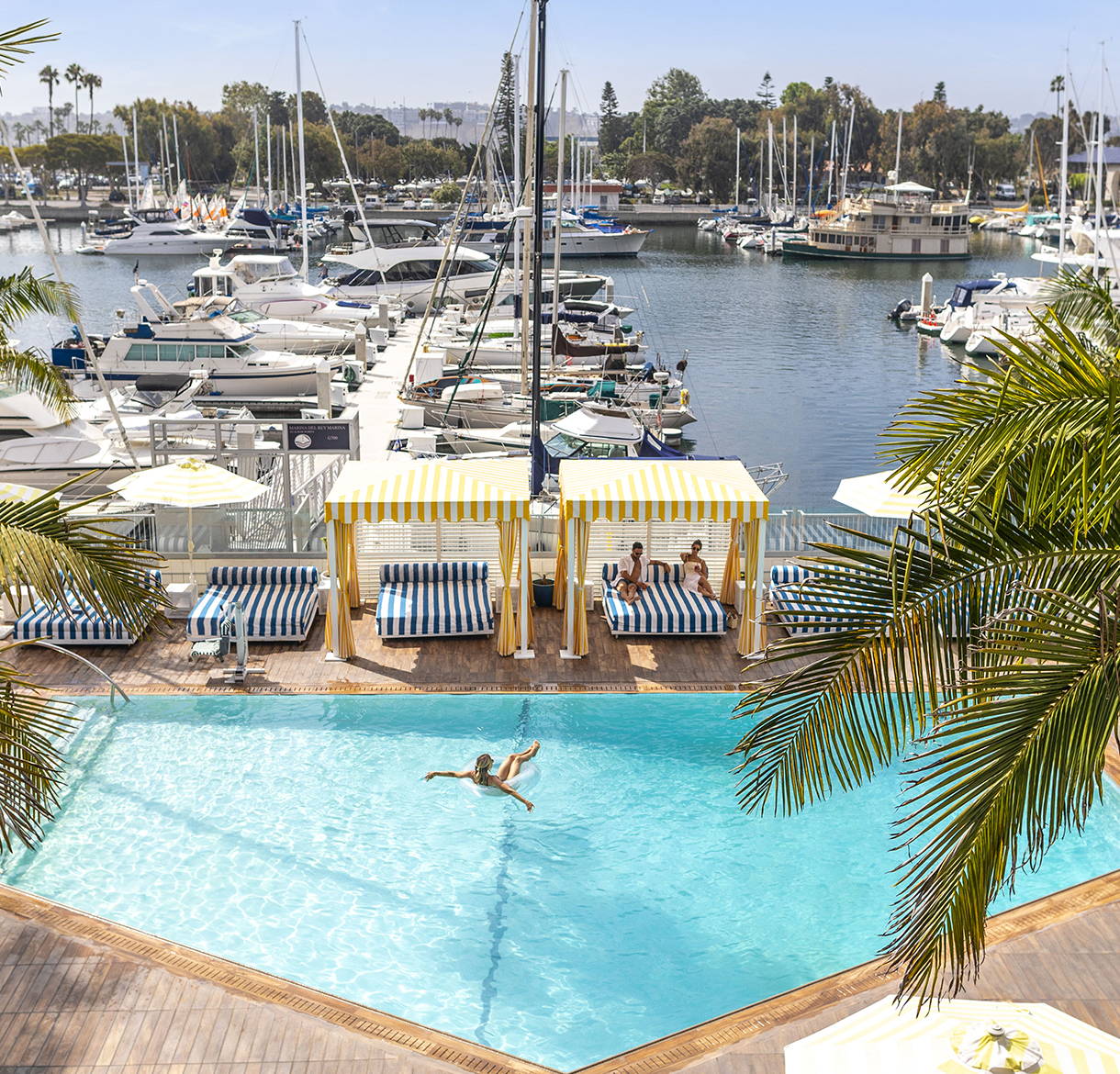 a person swimming in a pool with a marina and boats in the background