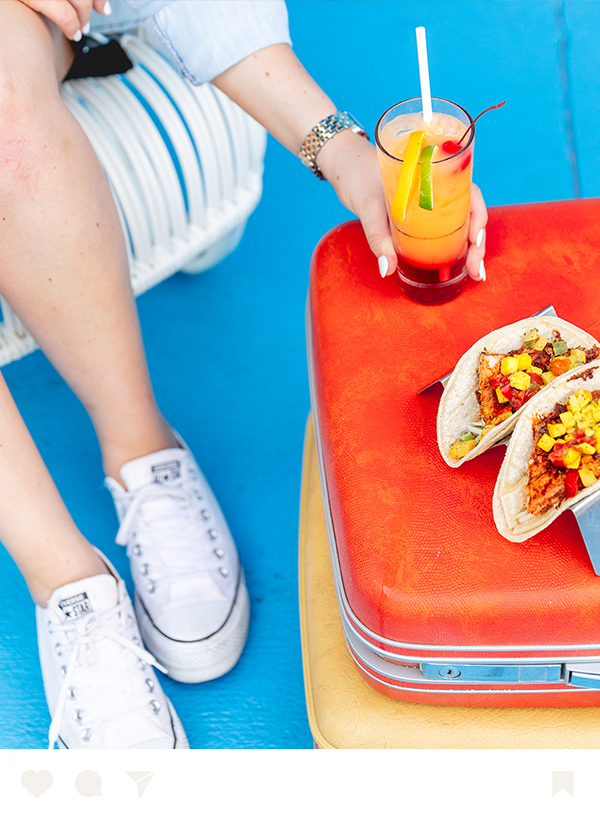 a person holding a drink next to a taco