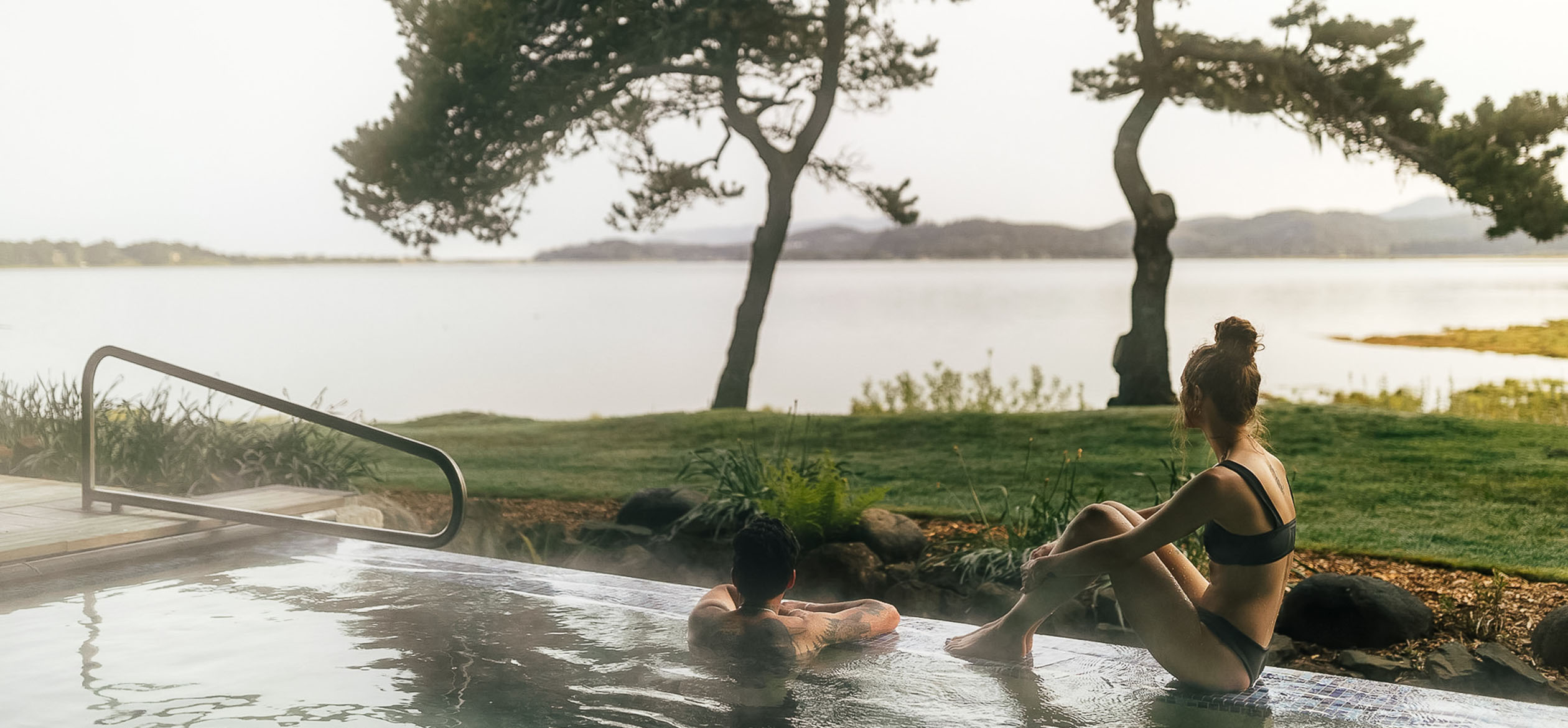 a man lying in a pool with a body of water in the background