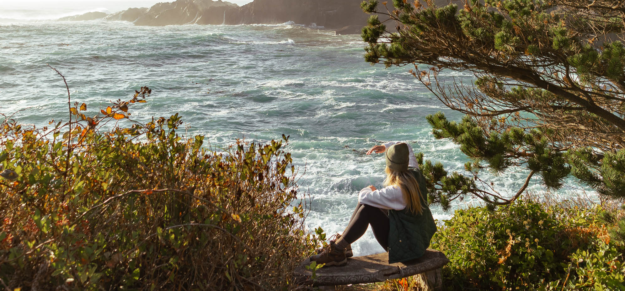 a woman sitting on a bench overlooking a body of water
