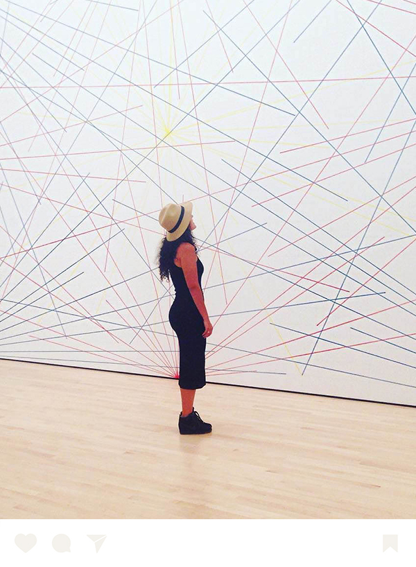 a woman in a hat looking at a large wall with lines