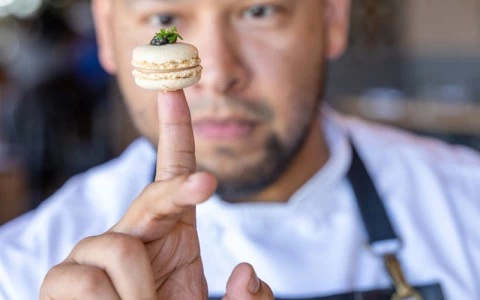 a man holding a small macaroon on his finger