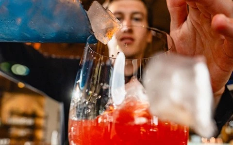 a person pouring a drink into a glass