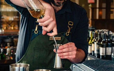 a man pouring liquid into a metal cup