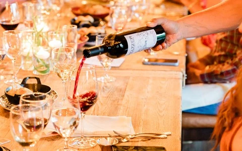 a person pouring wine into a glass