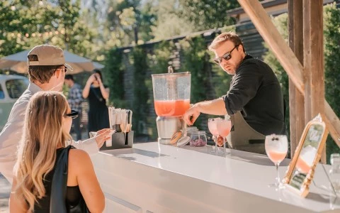 a man pouring a drink into a juice dispenser
