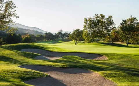 a golf course with sand bunkers and trees