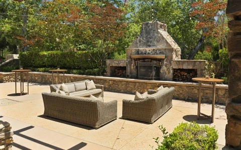 a patio with a stone fireplace and furniture