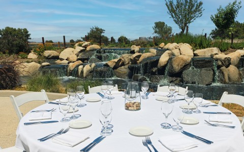 a table set for a dinner with water and rocks