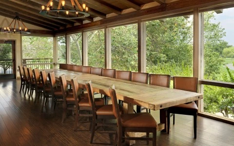 a long table with brown chairs in a room with windows