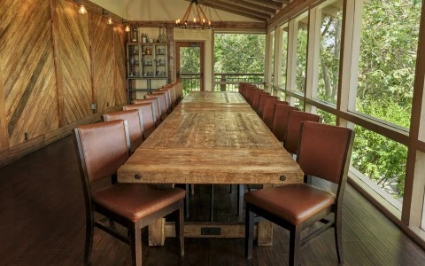 a large wooden table with brown chairs in a room with a porch