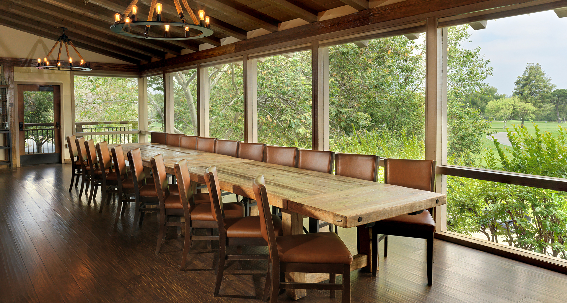 a long table with brown chairs in a room with windows