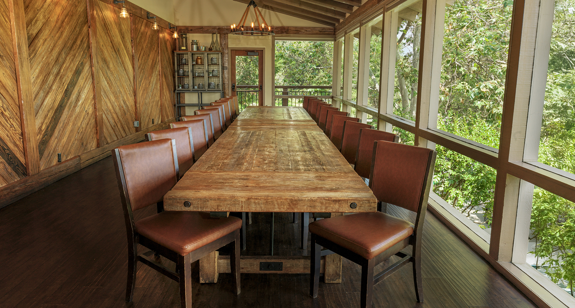 a large wooden table with brown chairs in a room with windows