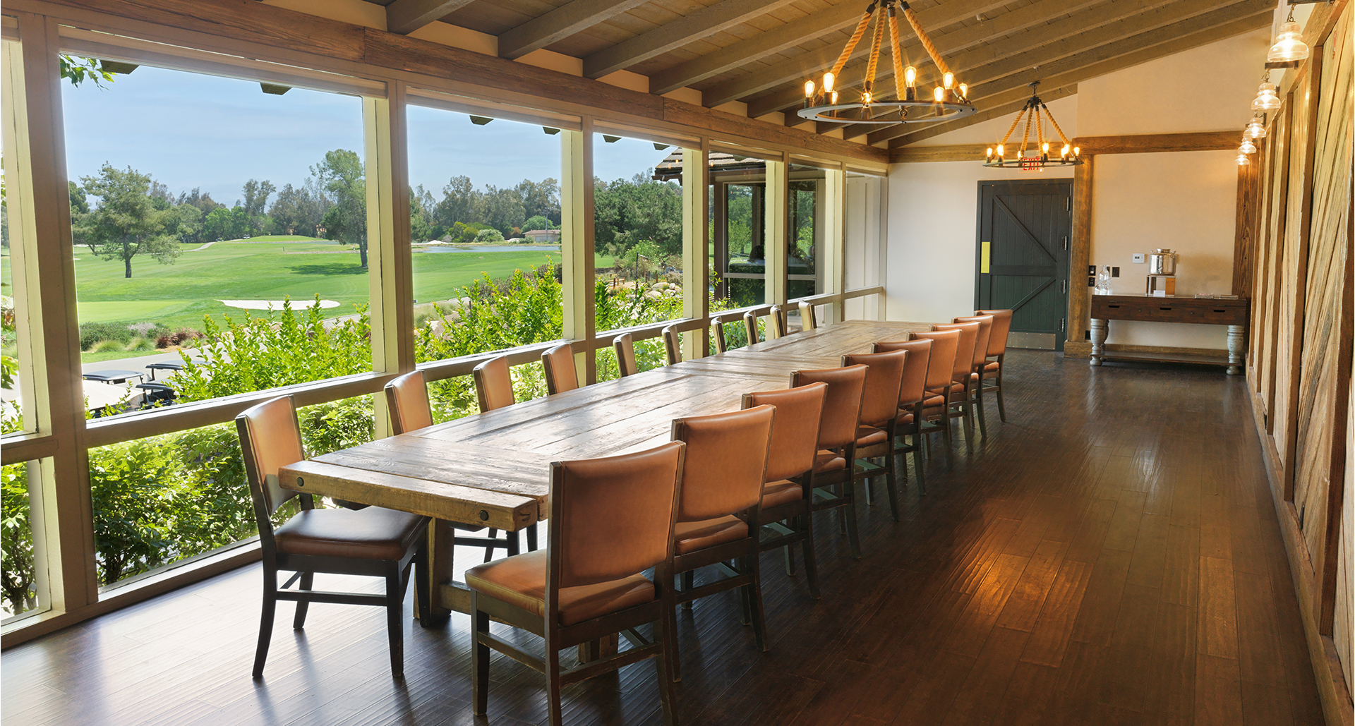 a long table with chairs in a room with a golf course view