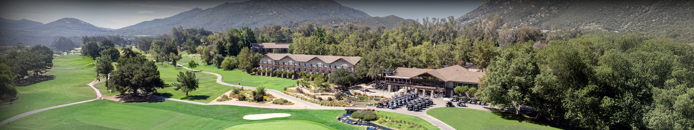 a golf course with a building and cars parked in front